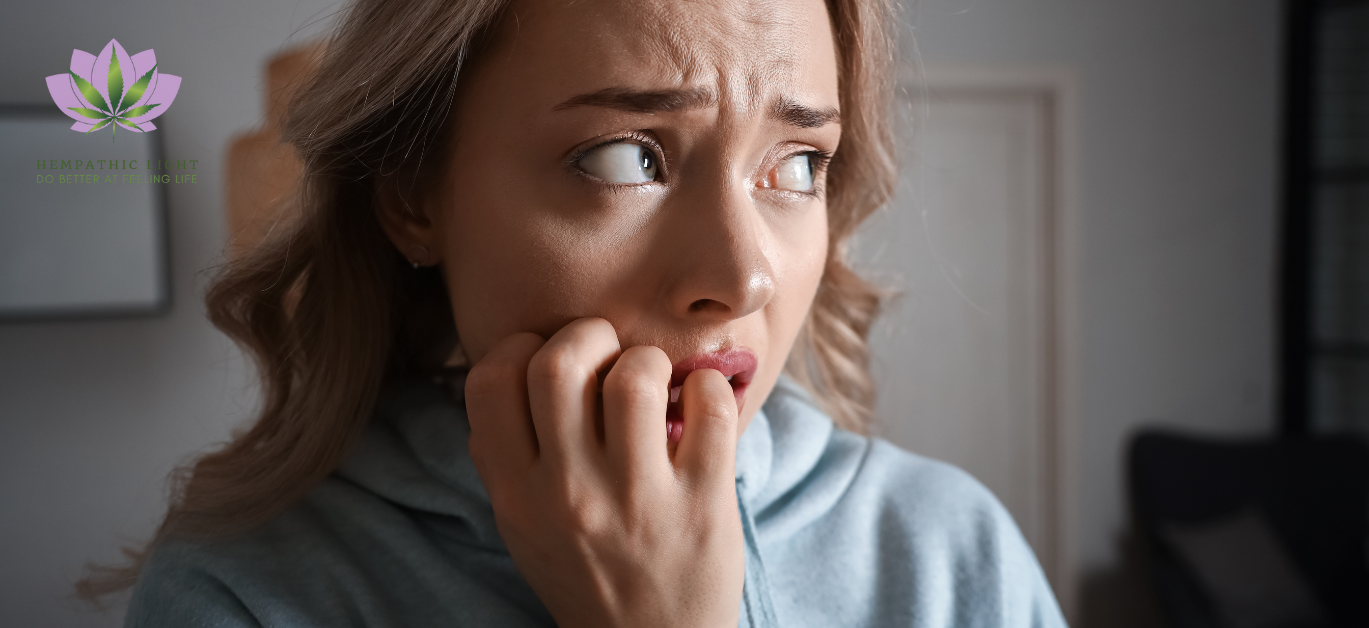 Jovem mulher com dedos na boca como quem rói as  unhas,  com uma expressão de medo extremo