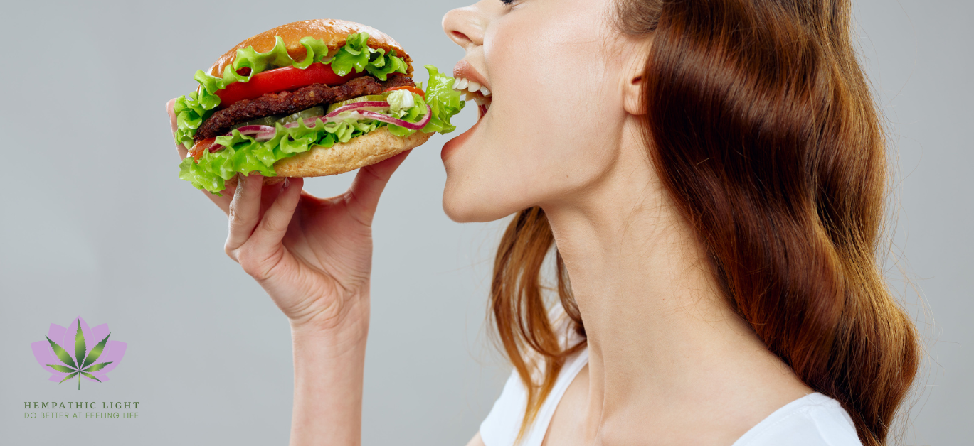 Perfil de uma mulher jovem a dar um dentada num hamburger